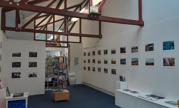 Interior with mid blue carpet, white walls and mahogany coloured beams in triangular formation at the ceiling. Regularly spaced landscape formatted ph